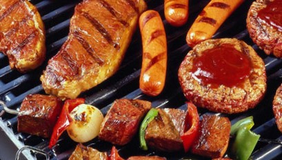 Diverse stukken vlees op een grill waaronder gegrilde biefstuk worstjes hamburgers met saus en vleesspiesjes met paprika en ui