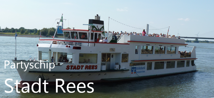 Partyschip Stadt Rees vaart over de rivier met veel passagiers op het zonnedek de witte rondvaartboot is duidelijk in beeld met water en oever op de achtergrond